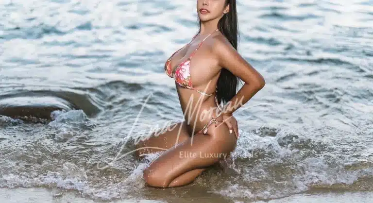 Elite bikini model kneeling in sea